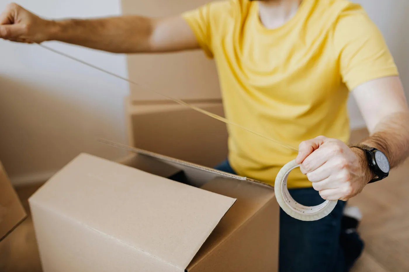 Holding a roll of clear packing tape over an open carton